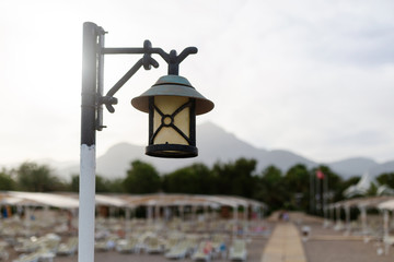 Street lamp on the beach. In the background is a beautiful view of the mountains.