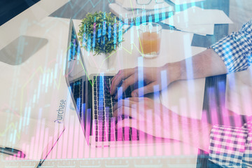 Multi exposure of graph with man typing on computer in office on background. Concept of hard work. Closeup.