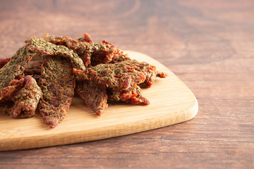 A Pile of Gourmet Cilantro Flavored Beef Jerky on a Wooden Cutting Board