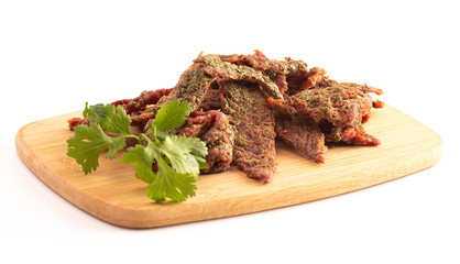 A Pile of Gourmet Cilantro Flavored Beef Jerky on a Wooden Cutting Board