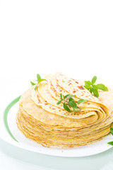 many fried thin pancakes in a plate, on white background.