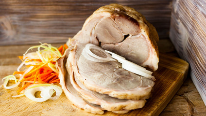 Baked pork ham on a chopping Board with vegetable spaghetti on a rustic wooden table