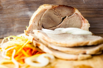Baked pork ham on a chopping Board with vegetable spaghetti on a rustic wooden table