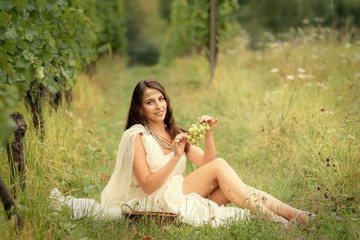 Young woman in tunic harvesting grapes