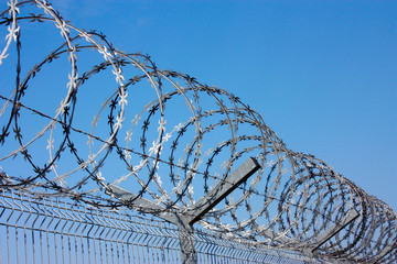 fence with barbed wire against the blue sky. Symbol of freedom of imprisonment