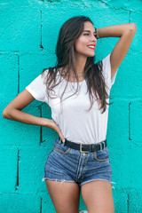 Beautiful brunette female standing by turquoise wall