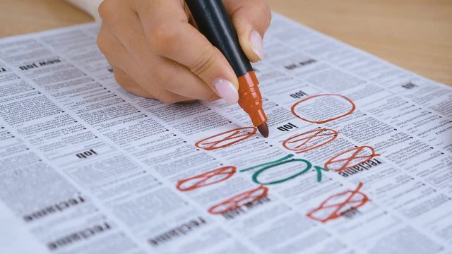 woman Looking for Job in a Newspaper and Marking Advertisement Using Red Pencil. 4K