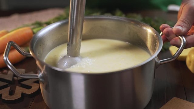 The cook uses hand blender to make mashed soup in the metal pan, cooking healthy food, mashed vegetables, Full HD Prores 422 HQ
