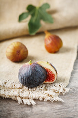 Ripe organic figs on the table. Group of purple and green figs on a farm wooden table with burlap cloth