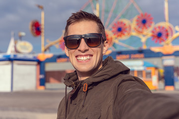 man taking a selfie in coney island. Luna park as background