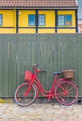 Fototapeta na wymiar Red bicycle against a green fence in the old part of Ribe, Denmark
