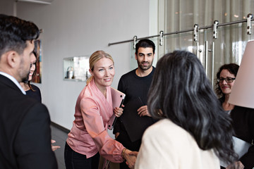 Businesswomen greeting colleagues in office lobby