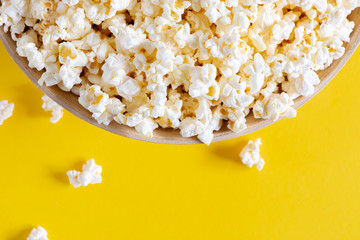 Big bowl of white salty popcorn on yellow background. Flat lay, top view, copy space