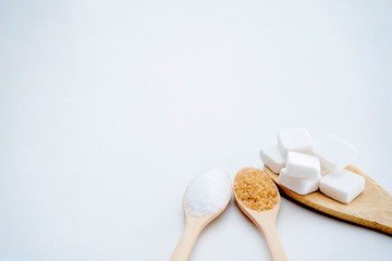 Fototapeta na wymiar White sugar, brown sugar, sugar cubes, placed in a wooden spoon.