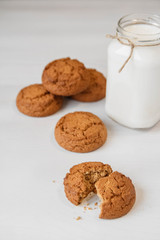 Milk in a glass jar and oatmeal cookies on a white table background. Copy, empty space for text
