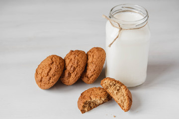 Milk in a glass jar and oatmeal cookies on a white table background. Copy, empty space for text