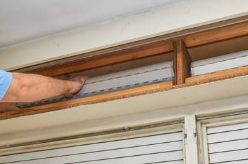 Man fixing an old blind in its wooden box
