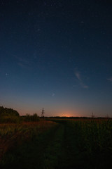Starry sky over the road in the field