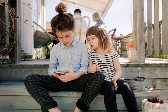 Sibling using smartphone while sitting on steps