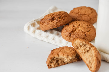 Milk in glass jar and oatmeal cookies near napkin on white table background. Copy, empty space for text