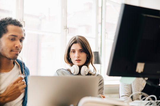 Computer programmers looking at laptop while programming in office
