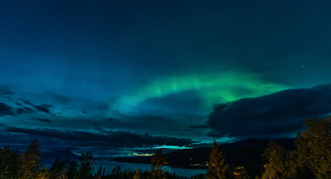 Ursa Major constellation, Aurora Borealis and heavy clouds over Norwegian mountains around Rossvatnet Lake, Northern Norway. Late summer night.