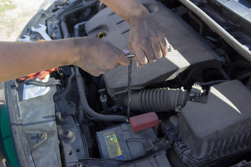 Car battery repair under the hood, female hands car repair
