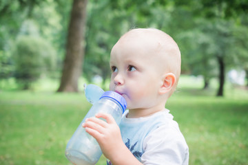 A child drinks water from a bottle while walking, baby health concept