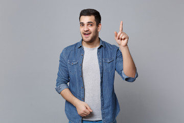 Handsome stylish unshaven young man in denim jeans shirt posing isolated on grey wall background...
