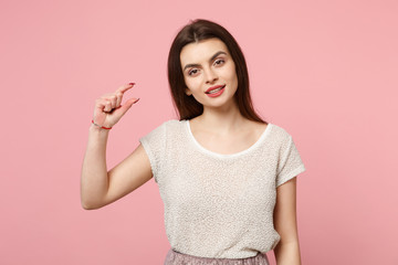 Beautiful young woman in casual light clothes posing isolated on pastel pink wall background studio portrait. People lifestyle concept. Mock up copy space. Gesturing demonstrating size with workspace.