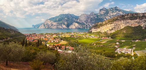 Lake coast with mountains and cliffs around, in the foreground village, green meadows, fields and...