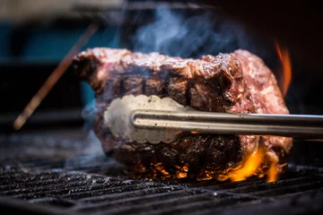 Poster Grilled ancho steak on barbecue grill with fire. Barbecue ancho steak. © carolaraujo