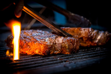Grilled ancho steak on barbecue grill with fire. BBQ Steak ancho meat steak. Barbecue ancho steak. - obrazy, fototapety, plakaty