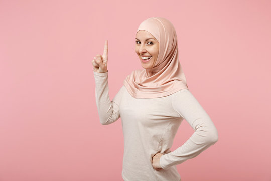 Smiling young arabian muslim woman in hijab light clothes posing isolated  on pink background studio portrait. People religious Islam lifestyle  concept. Mock up copy space. Pointing index finger up. Photos | Adobe