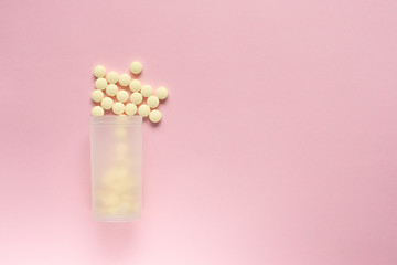Jar with scattered tablets on a pale pink background.