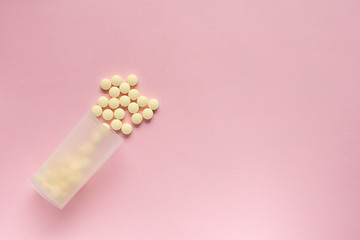 The jar lies diagonally with scattered tablets on a pale pink background.