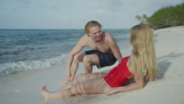Man walking from ocean then sitting on beach with woman / Petit Tabac, Tobago Cays, St. Vincent and the Grenadines