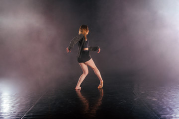 Shoeless female dance shows off her modern art dance moves while looking serious and devoted.