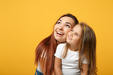 Woman in light clothes have fun with cute child baby girl 4-5 years old. Mommy little kid daughter isolated on yellow background studio portrait. Mother's Day love family parenthood childhood concept.