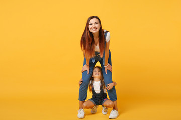 Woman in light clothes have fun with cute child baby girl 4-5 years old. Mommy little kid daughter isolated on yellow background studio portrait. Mother's Day love family parenthood childhood concept.