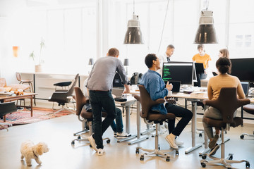 Male and female computer programmers discussing in creative workplace