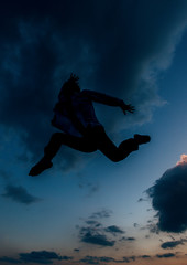 Man silhouette performing some moves above blue sky . Mixed media