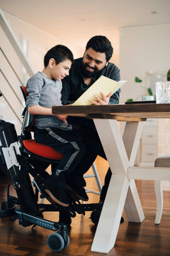 Father teaching autistic son while sitting at table