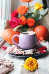  Cup of coffee, chocolate with spices, meringues, roses, pumpkins, leaves on a wooden surface on a window background, home comfort concept, Thanksgiving, autumn season
