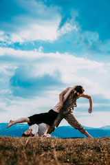 Two athletic young dancers making a performance on a mountain