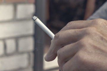 Man holding smoking cigarette in hand fingers close up