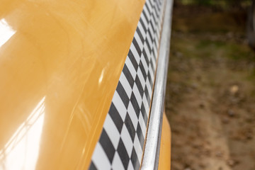 Checkered taxi sign on a yellow taxi car doors close up, copy space
