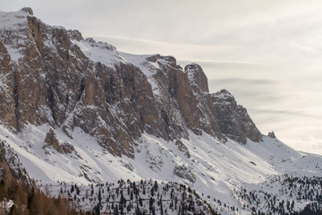 Sella in the Dolomites covered in Snow during a cloudy Day. Wide Landscape of the scenic Sella above Selva Val Gardena. Aerial Mountain