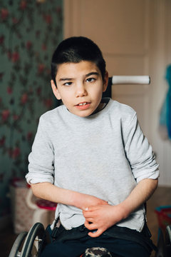 Portrait of disabled boy sitting on wheelchair at home