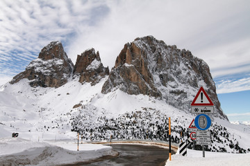 View of Langkofel, Sassolungo from Passo Sella. Snow covered Mountain in the Dolomites. Sellajoch Road with warning sign to use Chains on the vehicle